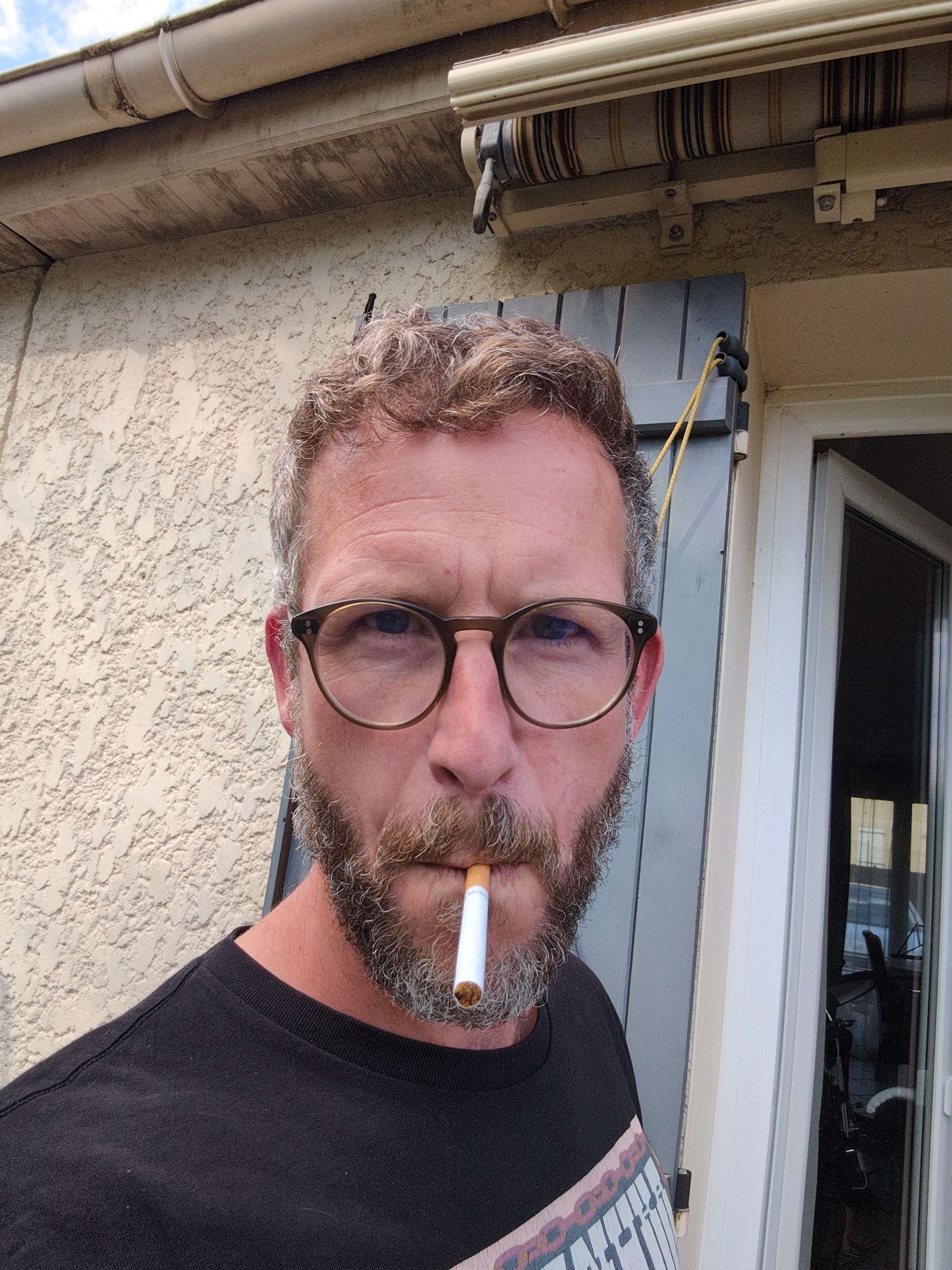 Portrait serré d'un membre du groupe NFNR avec lunettes et cigarette